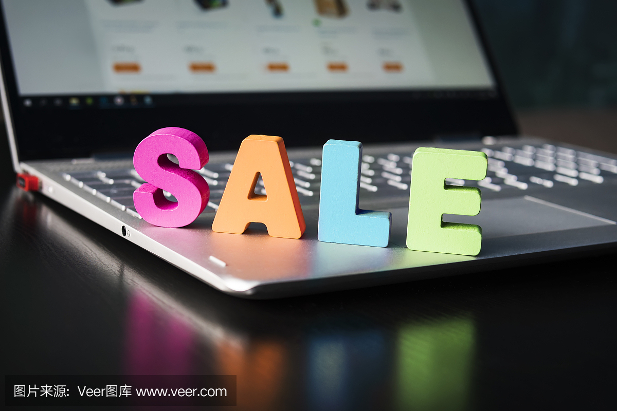 大的彩色字母在筆記本電腦上出售。銷售在網(wǎng)上商店的概念。打開筆記本與木字銷售鍵盤上的黑色桌子。網(wǎng)上購(gòu)物。買打折的東西。電子商務(wù)。